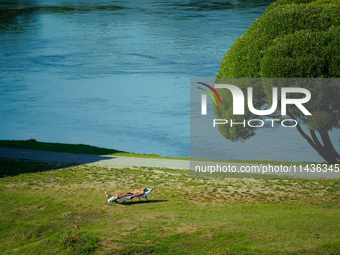 A man is seen sunbathing on the Narva River in Narva, Estonia on 24 July, 2024. Estonian authorities have closed the bridge that connects Ru...