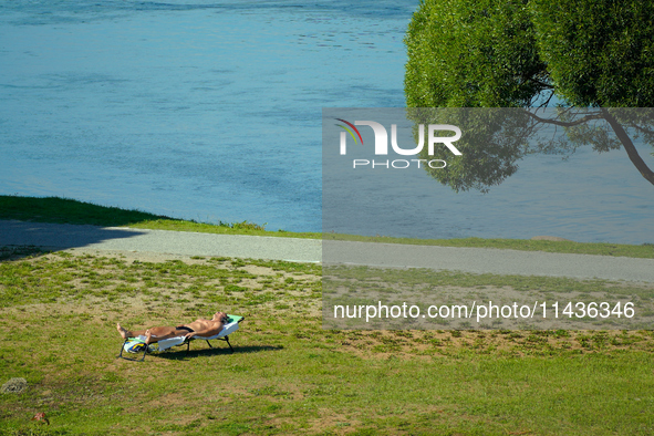 A man is seen sunbathing on the Narva River in Narva, Estonia on 24 July, 2024. Estonian authorities have closed the bridge that connects Ru...