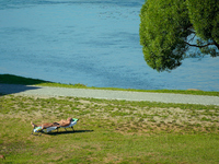 A man is seen sunbathing on the Narva River in Narva, Estonia on 24 July, 2024. Estonian authorities have closed the bridge that connects Ru...