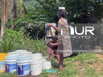 A woman is filling and carrying buckets of drinking water in Pathanamthitta, Kerala, India, on April 05, 2024. (