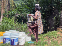 A woman is filling and carrying buckets of drinking water in Pathanamthitta, Kerala, India, on April 05, 2024. (