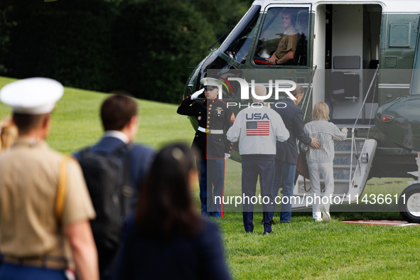 U.S. President Joe Biden, wearing a Team USA 2024 Olympics jacket, gestures jokingly to a U.S. Marine pilot as he boards Marine One en route...