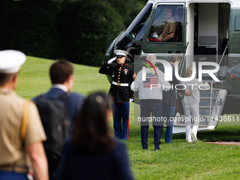 U.S. President Joe Biden, wearing a Team USA 2024 Olympics jacket, gestures jokingly to a U.S. Marine pilot as he boards Marine One en route...