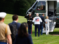 U.S. President Joe Biden, wearing a Team USA 2024 Olympics jacket, gestures jokingly to a U.S. Marine pilot as he boards Marine One en route...