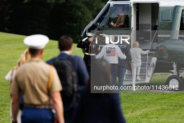 U.S. President Joe Biden, wearing a Team USA 2024 Olympics jacket, gestures jokingly to a U.S. Marine pilot as he boards Marine One en route...