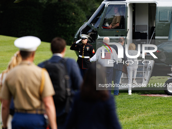 U.S. President Joe Biden, wearing a Team USA 2024 Olympics jacket, gestures jokingly to a U.S. Marine pilot as he boards Marine One en route...