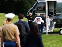 U.S. President Joe Biden, wearing a Team USA 2024 Olympics jacket, gestures jokingly to a U.S. Marine pilot as he boards Marine One en route...