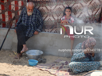 Displaced Palestinians from the eastern part of Khan Yunis are preparing to cook at a temporary camp set up in the grounds of a cemetery in...