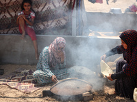 Displaced Palestinians from the eastern part of Khan Yunis are preparing to cook at a temporary camp set up in the grounds of a cemetery in...