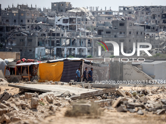 People are walking next to graves as displaced Palestinians from the eastern part of Khan Yunis are setting up a temporary camp in the groun...