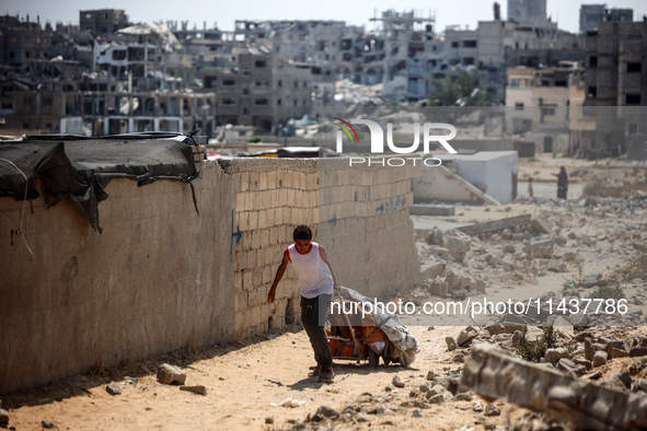 A Palestinian boy is walking next to graves as displaced Palestinians from the eastern part of Khan Yunis are setting up a temporary camp in...