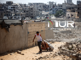 A Palestinian boy is walking next to graves as displaced Palestinians from the eastern part of Khan Yunis are setting up a temporary camp in...