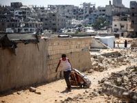 A Palestinian boy is walking next to graves as displaced Palestinians from the eastern part of Khan Yunis are setting up a temporary camp in...