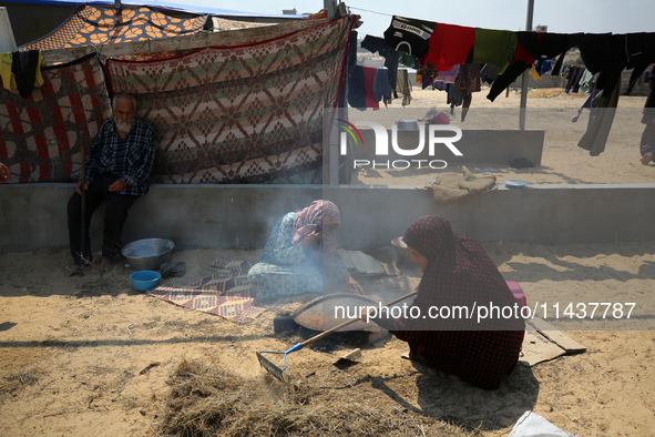 Displaced Palestinians from the eastern part of Khan Yunis are preparing to cook at a temporary camp set up in the grounds of a cemetery in...