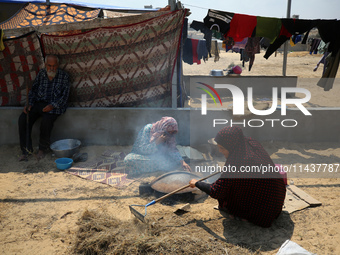 Displaced Palestinians from the eastern part of Khan Yunis are preparing to cook at a temporary camp set up in the grounds of a cemetery in...