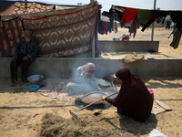 Displaced Palestinians from the eastern part of Khan Yunis are preparing to cook at a temporary camp set up in the grounds of a cemetery in...