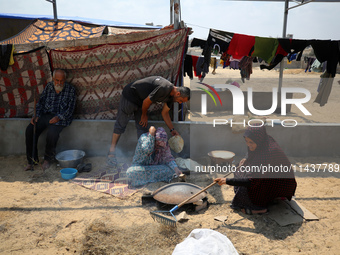 Displaced Palestinians from the eastern part of Khan Yunis are preparing to cook at a temporary camp set up in the grounds of a cemetery in...