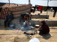 Displaced Palestinians from the eastern part of Khan Yunis are preparing to cook at a temporary camp set up in the grounds of a cemetery in...