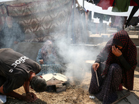 Displaced Palestinians from the eastern part of Khan Yunis are preparing to cook at a temporary camp set up in the grounds of a cemetery in...