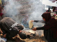 Displaced Palestinians from the eastern part of Khan Yunis are preparing to cook at a temporary camp set up in the grounds of a cemetery in...