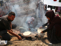 Displaced Palestinians from the eastern part of Khan Yunis are preparing to cook at a temporary camp set up in the grounds of a cemetery in...