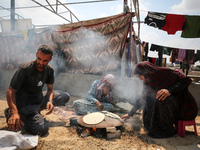 Displaced Palestinians from the eastern part of Khan Yunis are preparing to cook at a temporary camp set up in the grounds of a cemetery in...