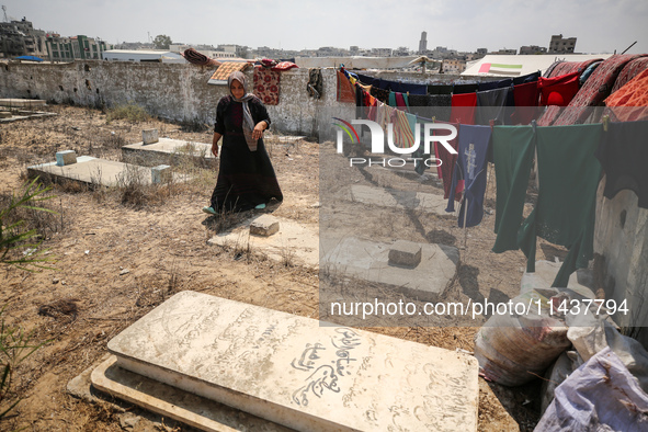 Displaced Palestinians from the eastern part of Khan Yunis are staying at a temporary camp set up in the grounds of a cemetery in the wester...