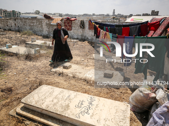 Displaced Palestinians from the eastern part of Khan Yunis are staying at a temporary camp set up in the grounds of a cemetery in the wester...