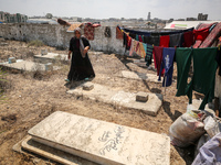 Displaced Palestinians from the eastern part of Khan Yunis are staying at a temporary camp set up in the grounds of a cemetery in the wester...