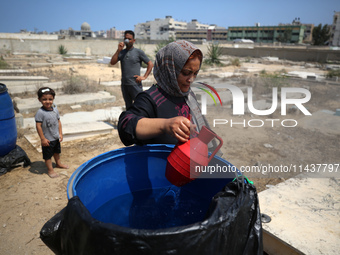 Displaced Palestinians from the eastern part of Khan Yunis are staying at a temporary camp set up in the grounds of a cemetery in the wester...