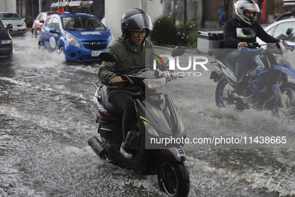 Motorcyclists are riding along Avenida Tlahuac in Mexico City after flooding is reported in various areas of the capital. 