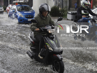 Motorcyclists are riding along Avenida Tlahuac in Mexico City after flooding is reported in various areas of the capital. (