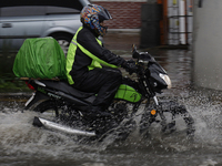 Motorcyclists are riding along Avenida Tlahuac in Mexico City after flooding is reported in various areas of the capital. (