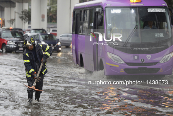 A firefighter is trying to unclog a drain after flooding is reported in various areas of Mexico City. 