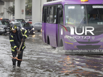 A firefighter is trying to unclog a drain after flooding is reported in various areas of Mexico City. (