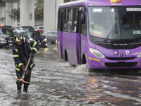 A firefighter is trying to unclog a drain after flooding is reported in various areas of Mexico City. (