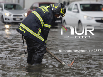 A firefighter is trying to unclog a drain after flooding is reported in various areas of Mexico City. (