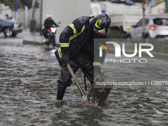 A firefighter is trying to unclog a drain after flooding is reported in various areas of Mexico City. (