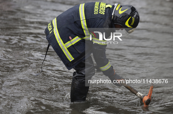 A firefighter is trying to unclog a drain after flooding is reported in various areas of Mexico City. 