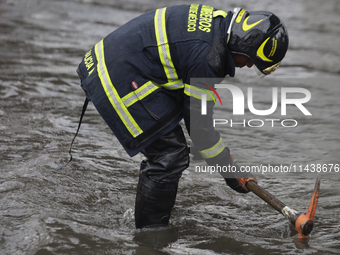 A firefighter is trying to unclog a drain after flooding is reported in various areas of Mexico City. (