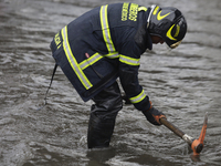 A firefighter is trying to unclog a drain after flooding is reported in various areas of Mexico City. (