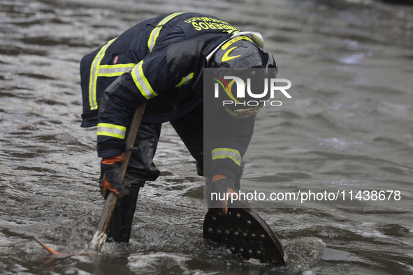 A firefighter is trying to unclog a drain after flooding is reported in various areas of Mexico City. 