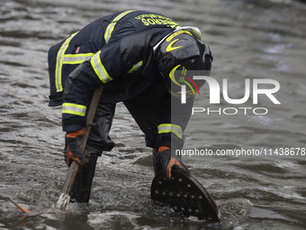 A firefighter is trying to unclog a drain after flooding is reported in various areas of Mexico City. (