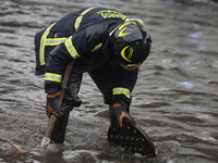 A firefighter is trying to unclog a drain after flooding is reported in various areas of Mexico City. (