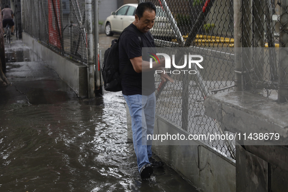 A person is trying to cross the street after flooding in various areas of Mexico City 