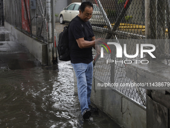 A person is trying to cross the street after flooding in various areas of Mexico City (