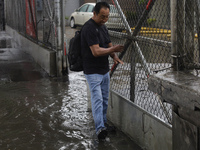 A person is trying to cross the street after flooding in various areas of Mexico City (