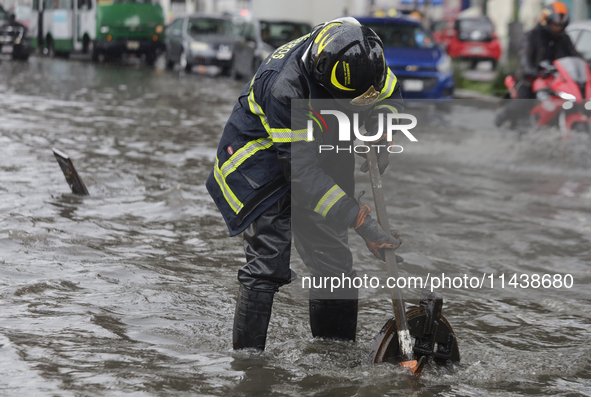 A firefighter is trying to unclog a drain after flooding is reported in various areas of Mexico City. 