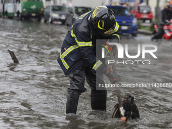 A firefighter is trying to unclog a drain after flooding is reported in various areas of Mexico City. (