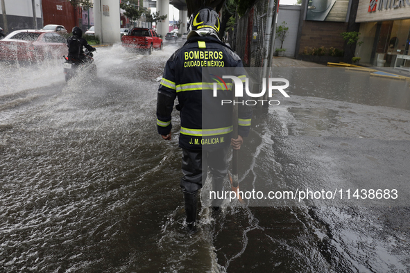 A firefighter is trying to unclog a drain after flooding is reported in various areas of Mexico City. 